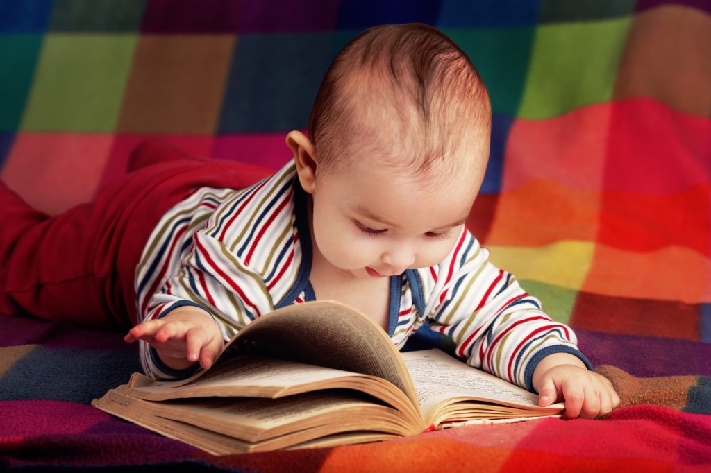 cute baby reading book on colorful background