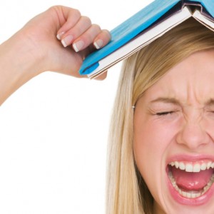 Angry student girl with book over head