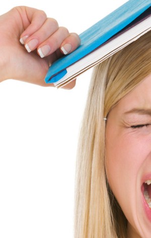 Angry student girl with book over head