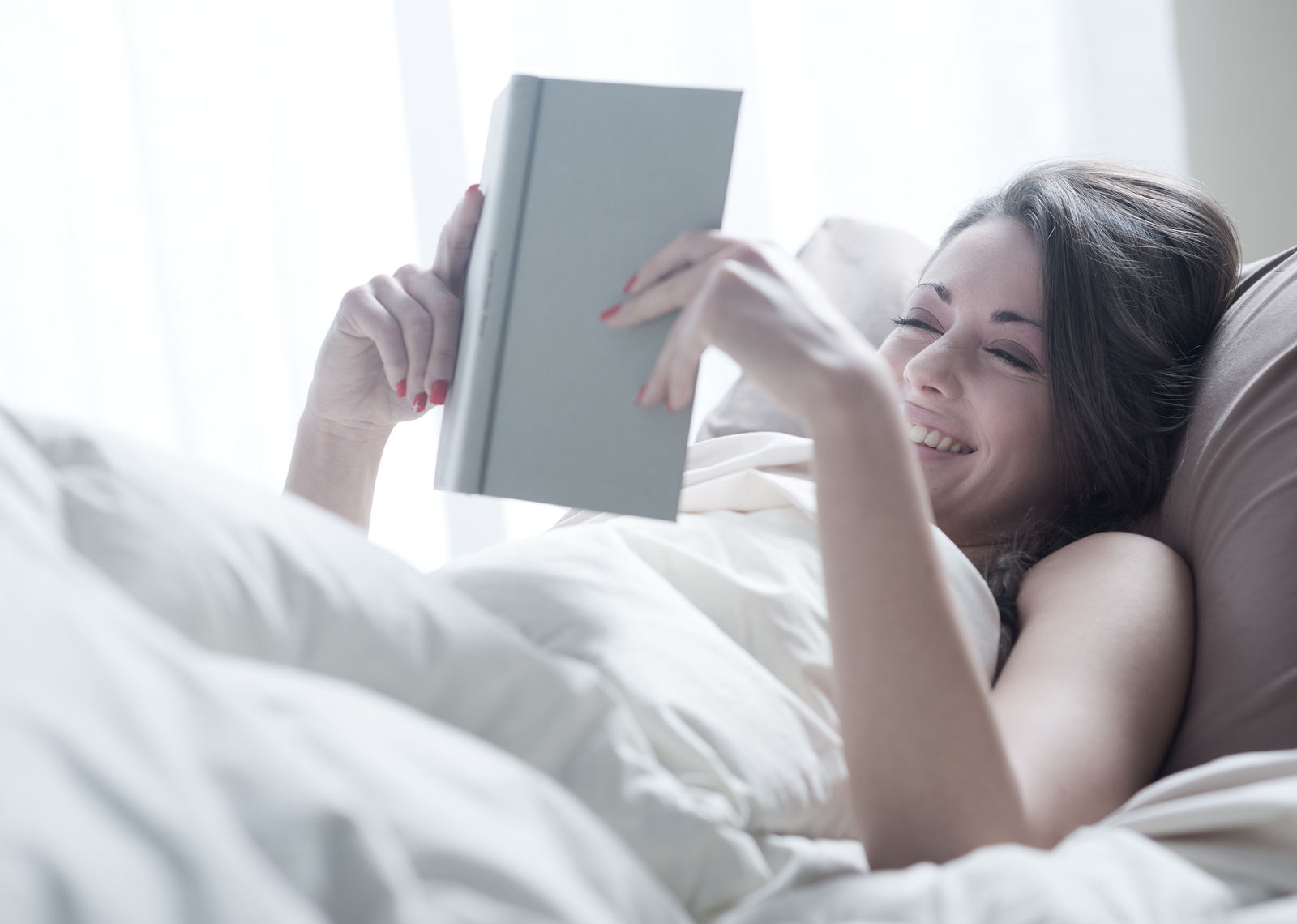 Woman lying in bed while reading a book