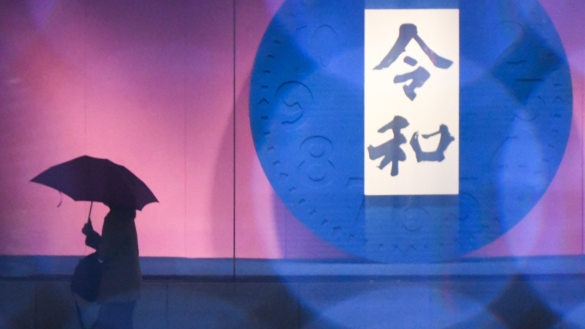 01 April 2019, Japan, Tokyo: A woman walks past by the name of the Japanese new era "Reiwa" which the country's new emperor Naruhito will reign. The word consists of two Japanese Kanji characters, "Rei" meaning order, command or good, while "Wa" means harmony. Photo: Ramiro Agustin Vargas Tabares/ZUMA Wire/dpa