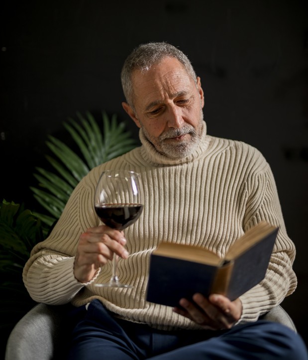 elderly-male-with-wine-reading-book_23-2148036726
