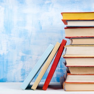 Stack of colorful hardback books, open book on blue background