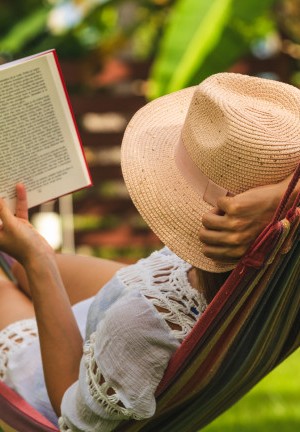 Happy beautiful woman in white dress relaxing in hammock.