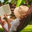 Happy beautiful woman in white dress relaxing in hammock.